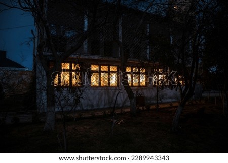 Old house with a Ghost in the forest at night or Abandoned Haunted Horror House in fog. Old mystic building in dead tree forest. Trees at night with moon. Surreal lights. Horror Halloween concept