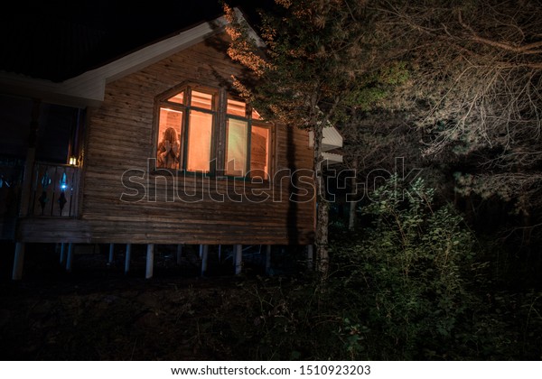 夜の森に幽霊のいる古い家 窓に影が映る 森の中の古い建物 超現実的な光 ホラーハロウィーンのコンセプト の写真素材 今すぐ編集