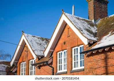 Old House With Plain Clay Roof Tiles, Snow On Pitched Rooftop In Winter. Loft Insulation And Home Improvement Concepts, UK