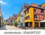 Old houses colorful facade, medieval buildings with colorful walls, shutters windows, street restaurant on pedestrian street in old town Colmar city historic centre, Alsace Grand Est region, France