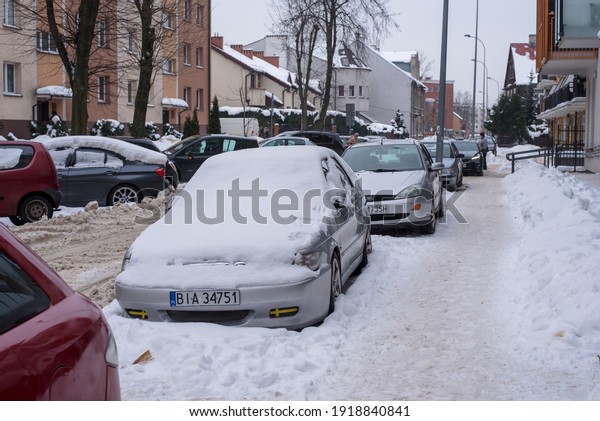 Old houses in the snow, Cars in the snow,\
snow-covered narrow streets, a winter city in Poland. Bialystok,\
Poland, February 2021