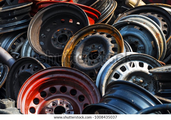 Old hubcaps with no logo.\
Some rusty, some not. In a heap and abandoned. Red one in\
front.