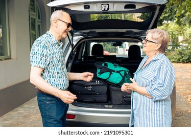 Old Husband And Wife Travelling On Vacation, Using Car For Road Trip Journey With Suitcase And Baggage. Going On Retirement Holiday With Luggage And Travel Bags, Leaving House During Summer.