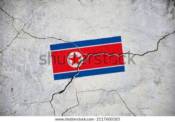 An old image of the flag of North Korea on a wall
with a crack. A crisis.