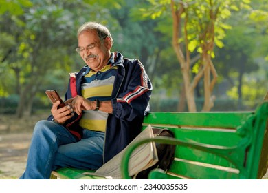 Old indian man using smartphone at park. - Powered by Shutterstock