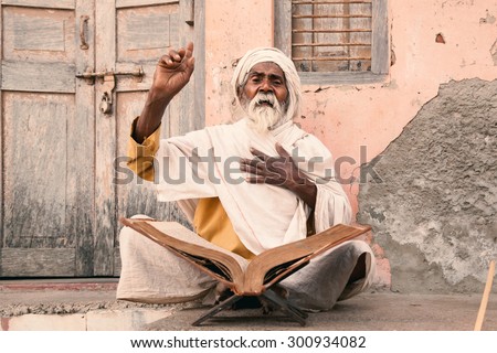 Old indian sadhu (saint) sitting and speak up sacred texts near the temple. 