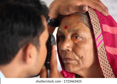 Old Indian woman in pink mantilla from Rajasthan getting eyes tested. Eye camp. Eye patient. Weak eyesight. Eye Health. Eye examination by doctor. Healthcare to elderly. 