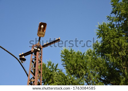 Old industrial metal street lamp on rusty support with cabel and tree on background