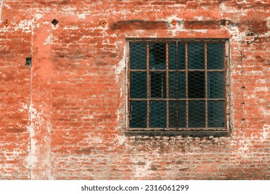 Old industrial metallic grid window with mullion and muntin on ruined factory building, broken glass and worn brickwall