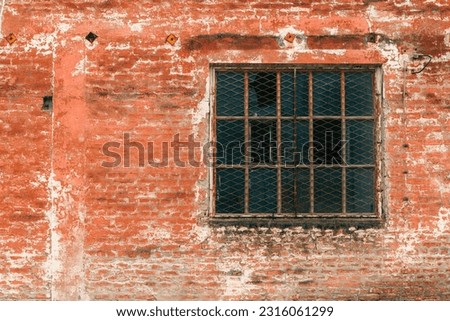 Old industrial metallic grid window with mullion and muntin on ruined factory building, broken glass and worn brickwall
