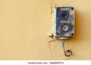 An old industrial push button switch on a plastered wall. Selective focusing.