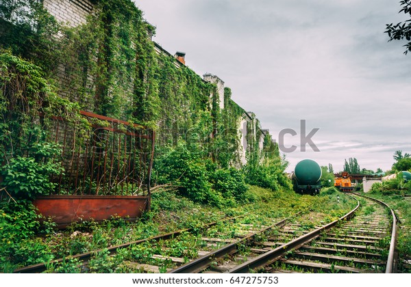 Old industrial railroad\
station platform, overgrowth with green grass, post apocalypse\
urbex concept