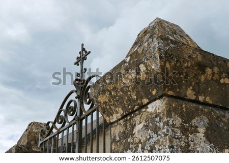 Old iron cemetery gate against an ominous sky with clouds in Cornac Lot Occitanie in Southern France