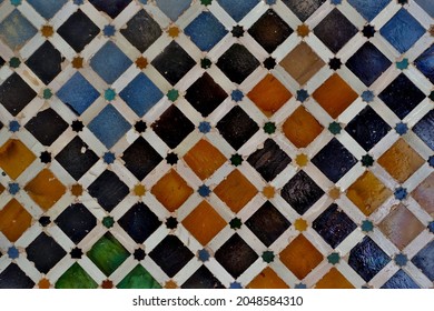 Old Islamic tiles (also known as zellige or azulejos) with traditional geometric patterns decorating a wall of the Nasrid Palaces inside the Alhambra. Granada, Andalusia, Spain. - Shutterstock ID 2048584310