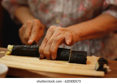 Old Japanese woman cutting handmade sushi roll in South East Asia - Powered by Shutterstock