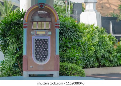 Old Jukebox Stands Among Green Bushes