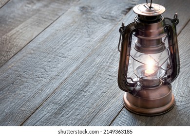 old kerosene lantern with burning light, antique vintage lamp on wooden table