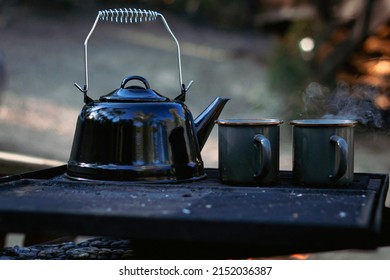 Old Kettle With Smoke Above The Titanium Mug Near The Fire Camp In A Morning.