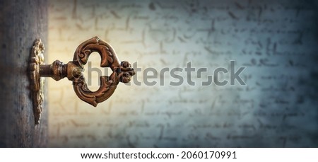 An old key in a keyhole on the background of an ancient manuscript, macro photography. Retro style. The key to knowledge. Concept and idea for history, education, religion, security background.