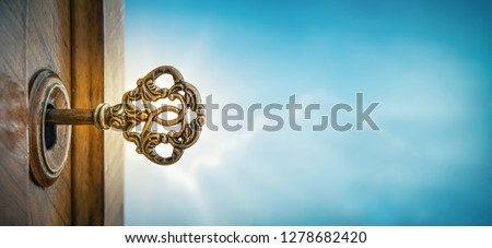 Old key in keyhole on sky background with sun ray . Concept, symbol and Idea for History, business, security, religion background.