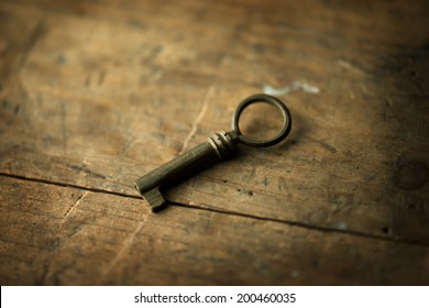 Old key on grungy wooden table. Shallow depth of field.