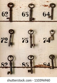 Old Keys With Numbers Hanging On A Weathered Wall Of An Old Hotel