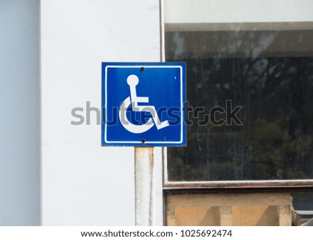 Old label disabled symbol in the parking. Label for wheelchair on the rust post.