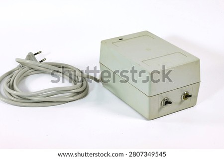 Old laboratory microscope power supply unit with integrated electrical cable, isolated on white. Scientific accessory for microscope illumination systems and optical laboratory equipment.