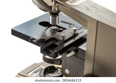 Old laboratory microscope with two objective lenses, eyepiece and metal stage, photographed from a side angle.