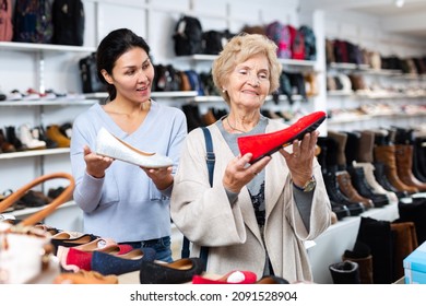 Old Lady Choosing New Shoes In Shoeshop. Asian Woman Consulting Her About Footwear.