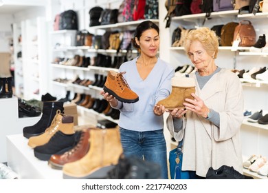 Old Lady Choosing New Shoes In Shoeshop. Asian Woman Consulting Her About Footwear.