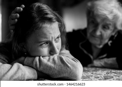 Old Lady Grandma Comforting A Crying Little Girl Granddaughter. Black And White Photo.