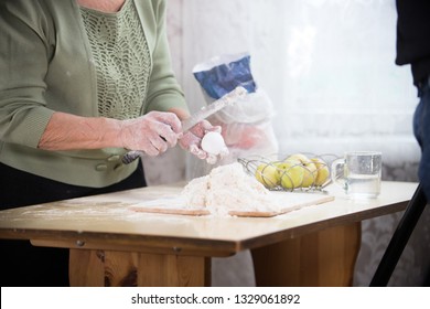 An Old Lady Making Little Pies. Making The Dough On The Desk. Breaking An Egg