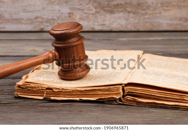 Old law book concept. Opened worn book with wooden\
court gavel.