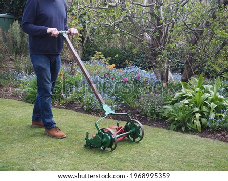 Old lawnmower being used in the garden to cut the grass
