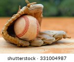 An old leather baseball mitt, or glove with a worn baseball laying on a home plate. There is clay around. Home plate needs to be dusted off. Shallow depth of field. Horizontal composition. Copy space