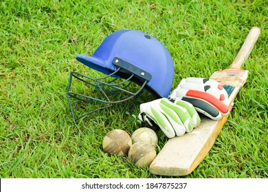 Old leather cricket ball, bat, helmet and glove on the green grass court, concept for practicing cricket sport after school of Asian students. - Powered by Shutterstock