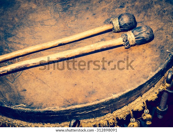 Old leather drum and drumsticks - membrane\
musical instrument. Ancient ethnic music on a folk festival.\
Timpani or kettledrums - old musical instruments in percussion\
family of classical\
orchestra.