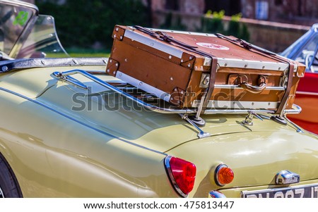 old leather suitcase on the luggage rack of yellow vintage car
