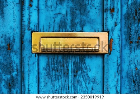 Old letterbox or mailbox slot on worn wooden blue door with paint peeling off