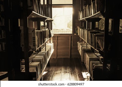 In The Old Library, The Books On The Shelves Were Cluttered, The Light Shining Out Of The Window In A Lonely Atmosphere, Vintage Style.