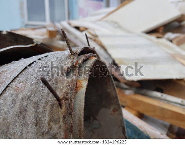 Old linoleum with nails and old boards in a\
pile of construction debris after\
repair