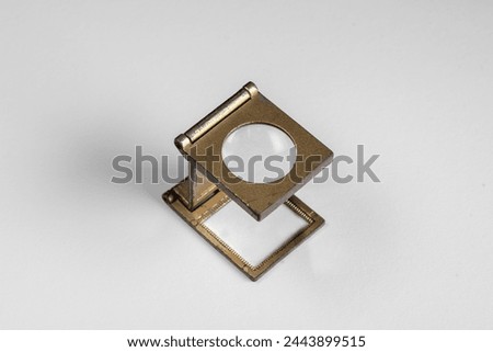 old lithographic loupe with metal frame and brass-toned glass lens