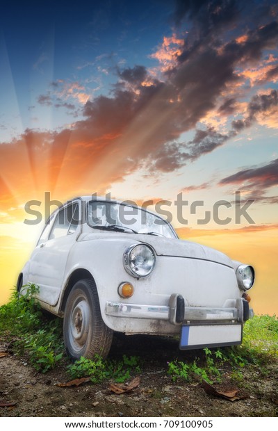 Old\
little travel car on a hill against sunset\
sky.