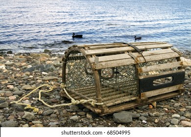 Old Lobster Trap: old handmade wooden lobster trap on pebble beach in the Maritime Provinces of Canada