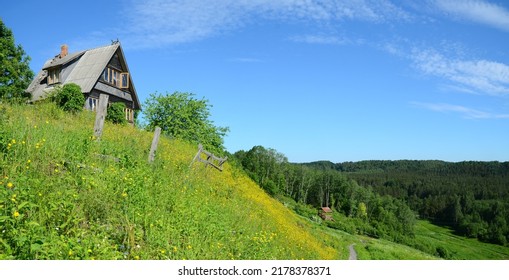 An old logs house on the top of the hill in summer sunny day. Green hill and blue sky, summer landscape, panorama