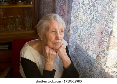 Old Lonely Woman Sitting Near The Window In His House And Looking And Dreaming