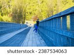 Old Lower Shotover Bridge, a historical bridge in Queenstown, New Zealand, with a person leaning on the railing, admiring the surrounding greenery in daylight