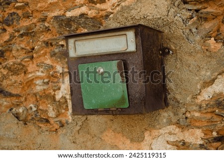 Old mailbox fixed to a wall of a ruined house
