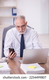 Old male employee and too much work in the office - Shutterstock ID 2254499807